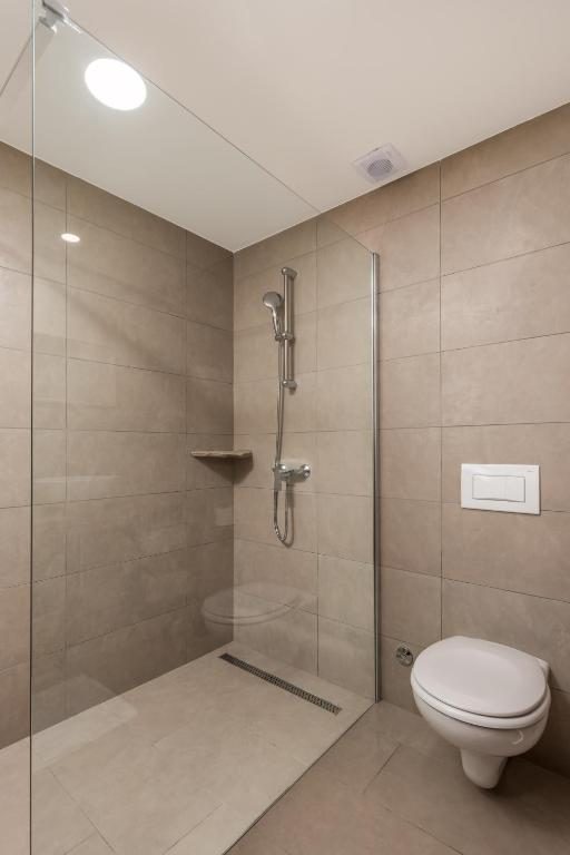 Moderna kupaonica s walk-in tušem i pločicama u zemljanim tonovima